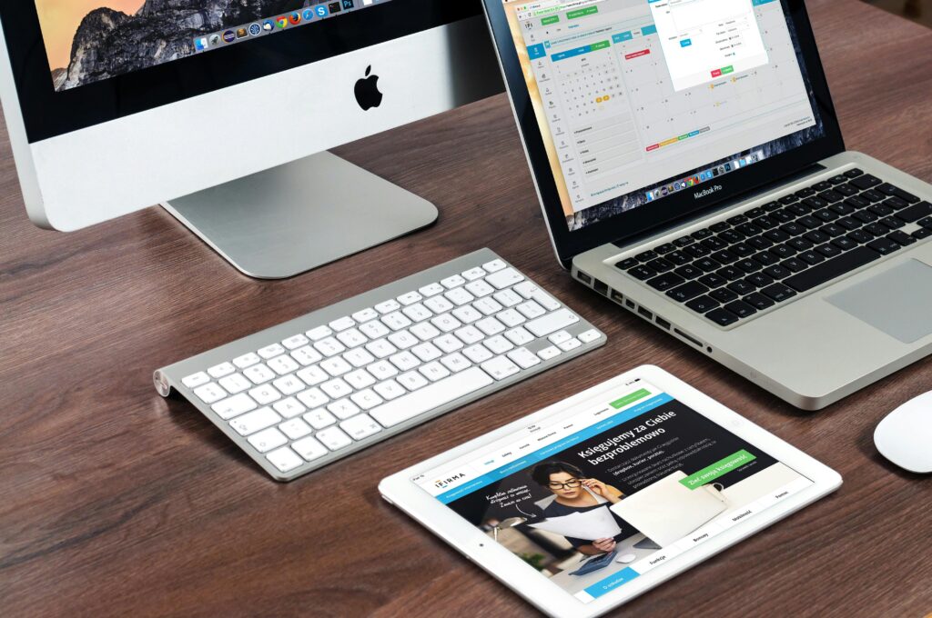 A sleek office desk setup featuring Apple devices: iMac, MacBook, and iPad.